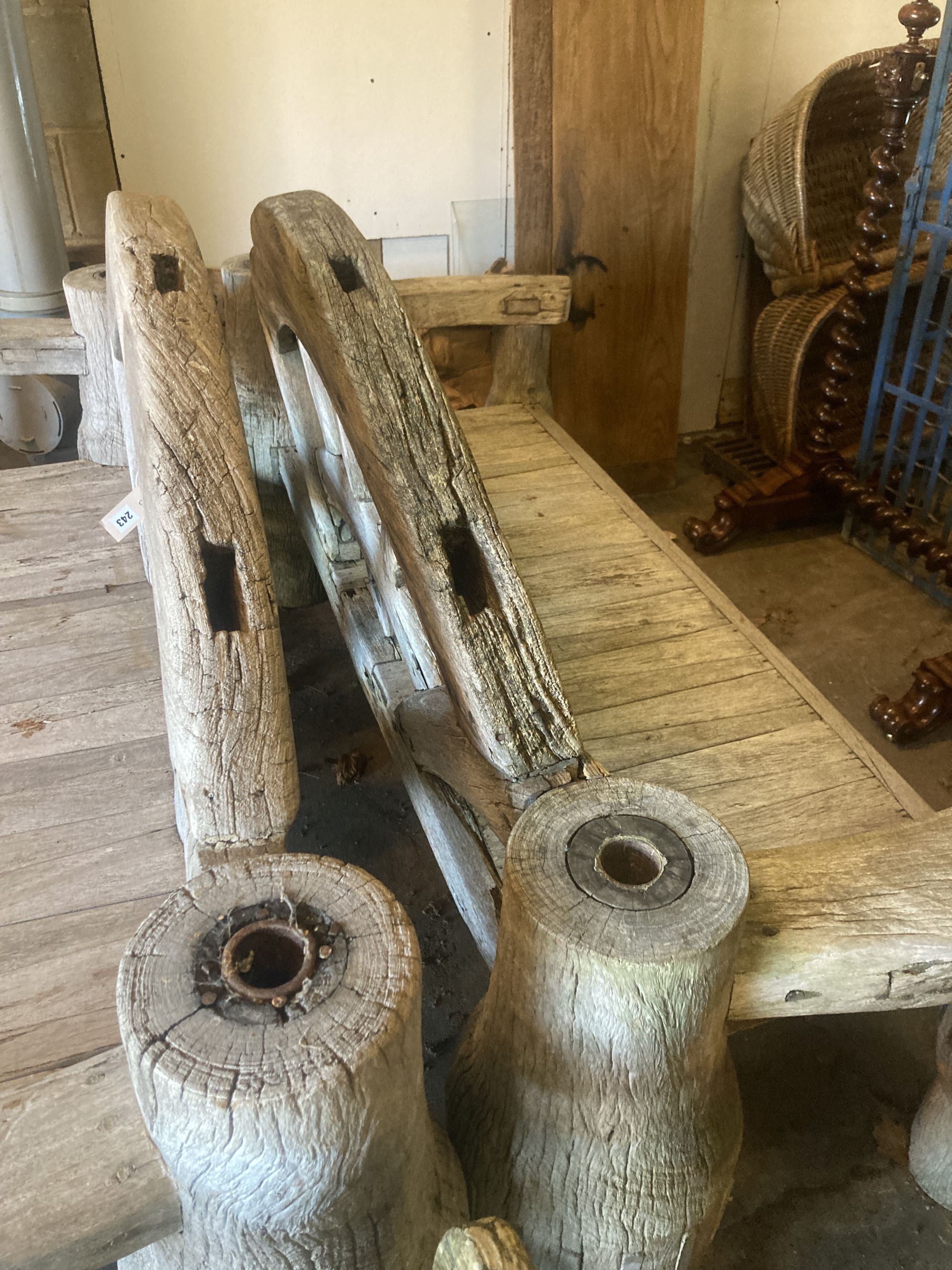 A pair of weathered hardwood cartwheel and hub garden benches, width 184cm depth 75cm height 105cm